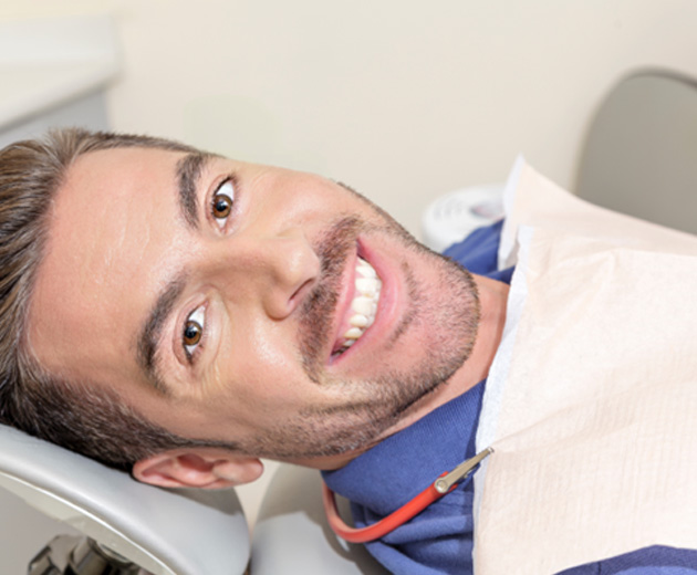 Man lying back in oral surgery chair smiling