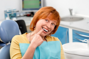 Woman pointing at her new dental implants and smiling