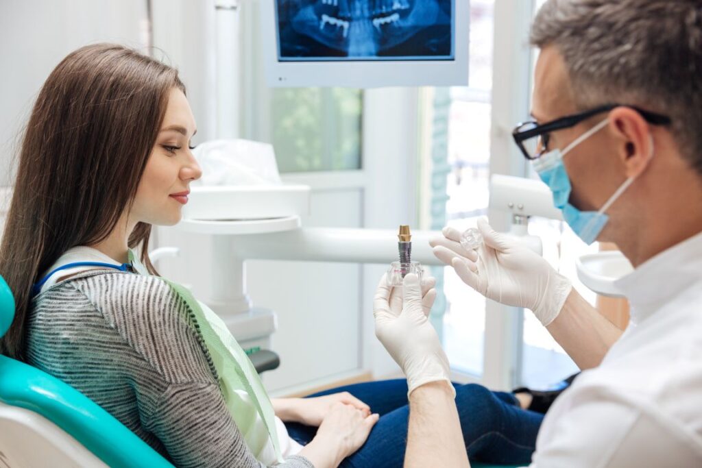 A dentist showing a patient a model of a dental implant